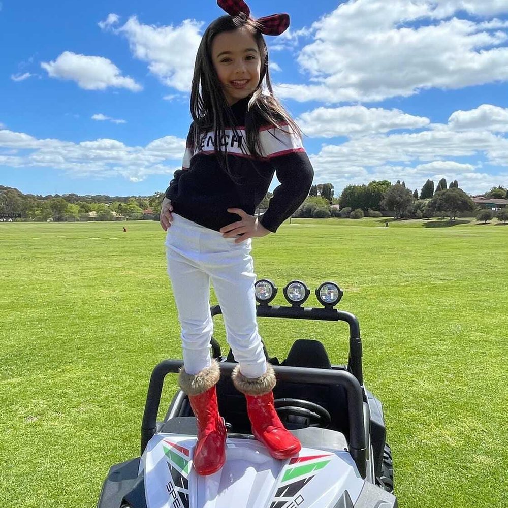 Little Riders 24V 4x4 beach buggy ride-on - girl standing on the bonnet of her white buggy