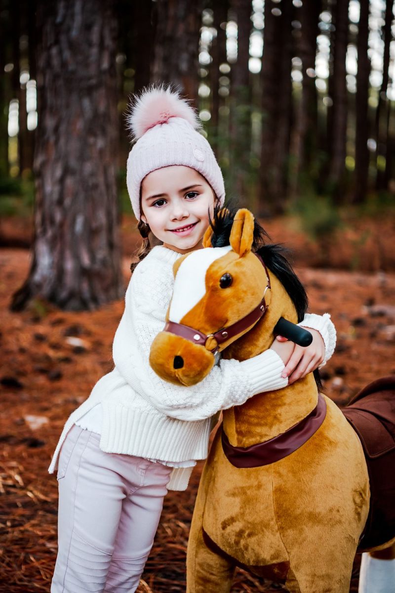 Little Riders brown ride-on horse toy - girl hugging her brown ride-on horse