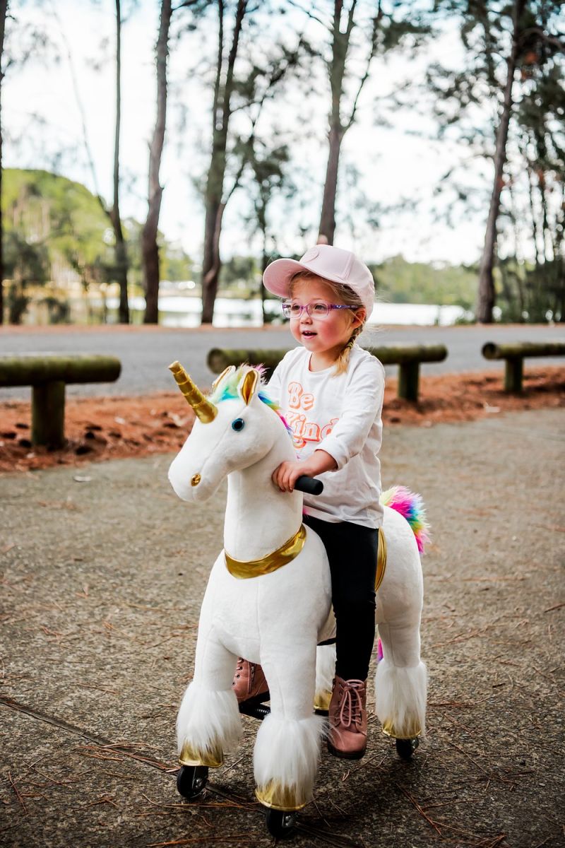 Little Riders rainbow unicorn ride-on toy - toddler riding her rainbow unicorn by the lake