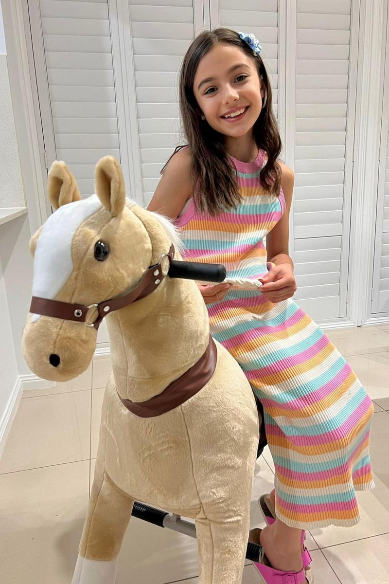 Little Riders light brown ride-on horse toy - girl smiling while riding her ride-on horse