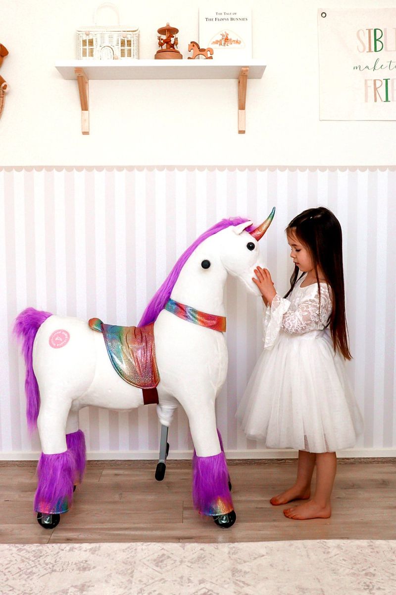 Little Riders unicorn ride-on toy - girl patting her rainbow saddle unicorn