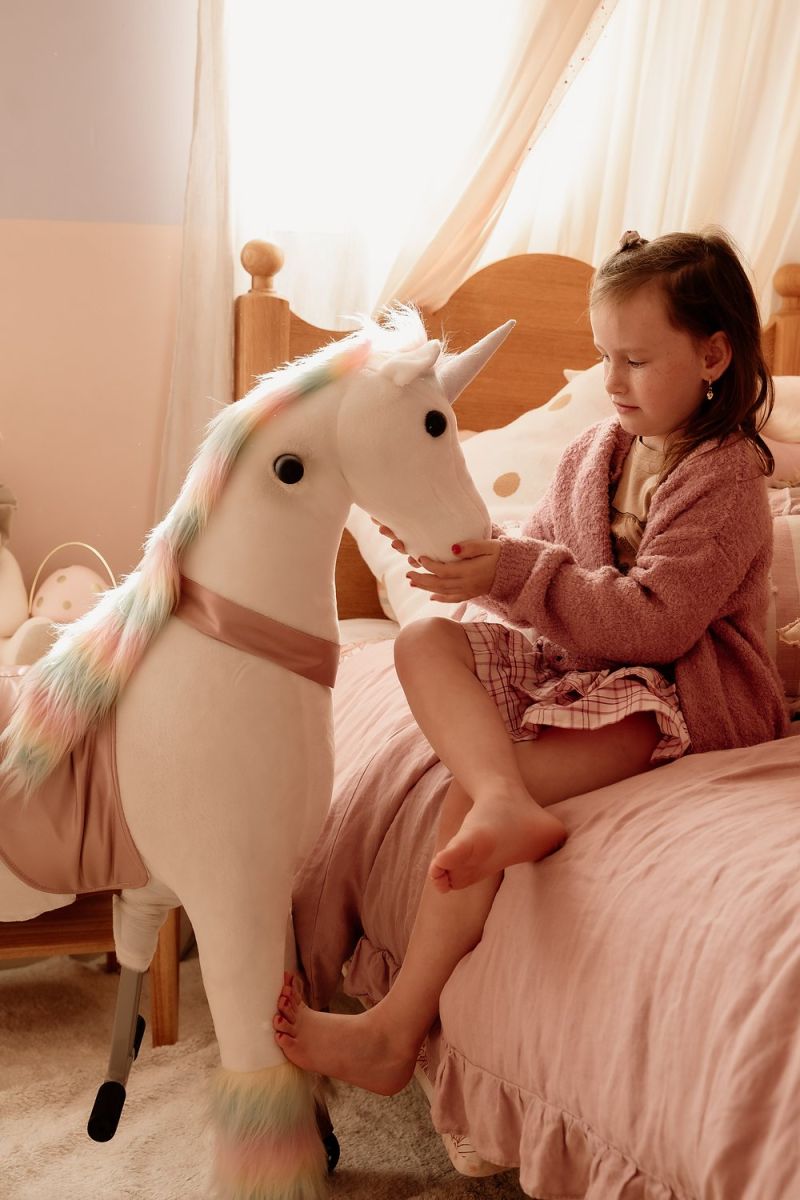 Little Riders unicorn ride-on toy - girl stroking her unicorn in a pink bedroom