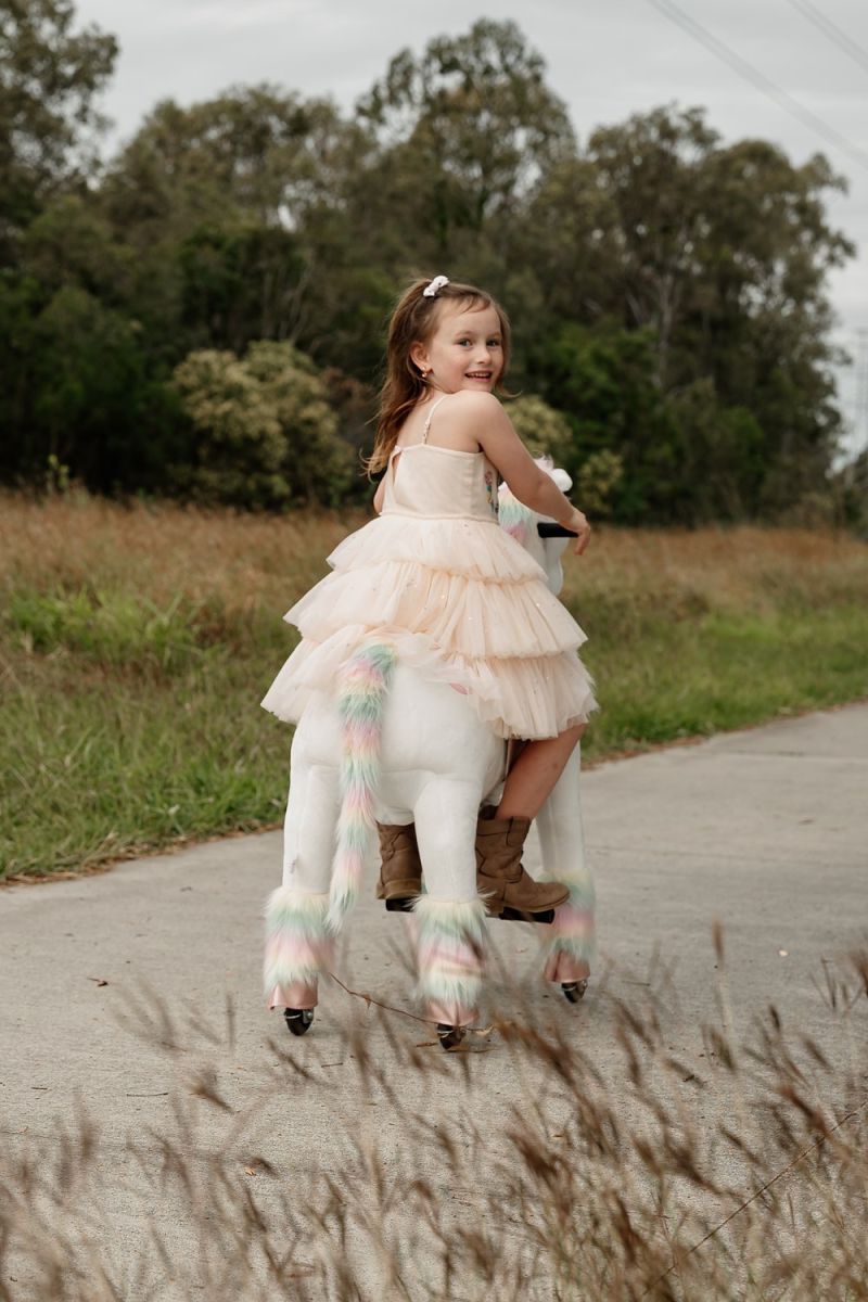 Little Riders unicorn ride-on toy - girl riding her unicorn down the path