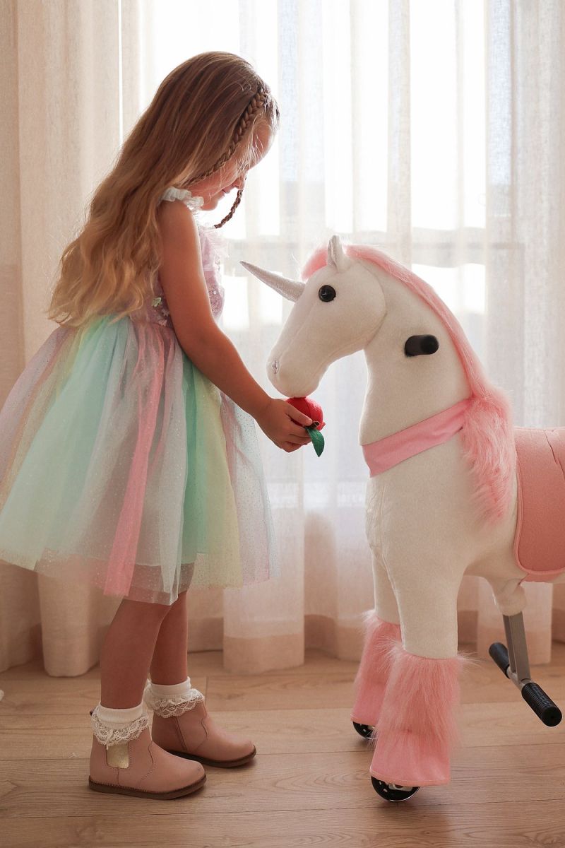 Little Riders pink unicorn ride-on toy - girl feeding her pink unicorn an apple